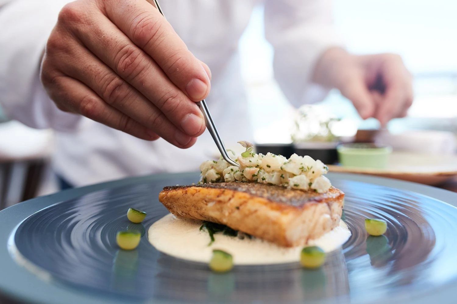 Chef placing the final garnish on a plated fish dish at the St Barth Gourmet Festival in Saint-Barthélemy — photograph by Michaël Gramm