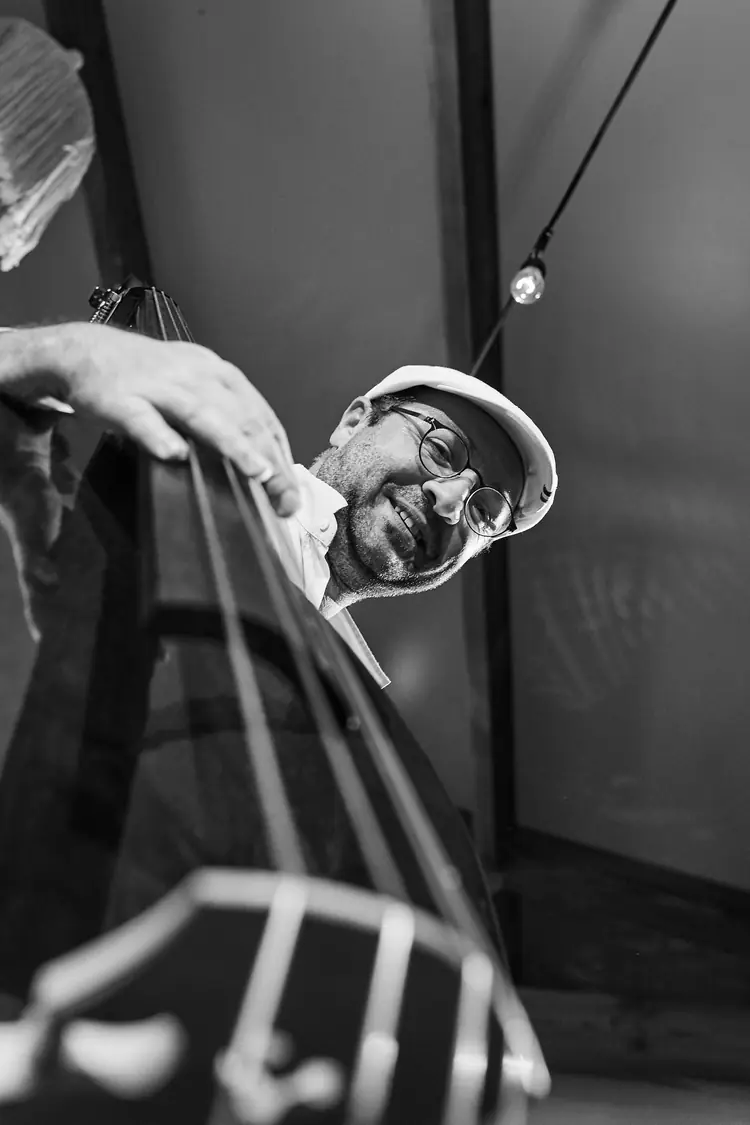 Low-angle view of a double bassist performing in black and white — Jazz photography by Michaël Gramm