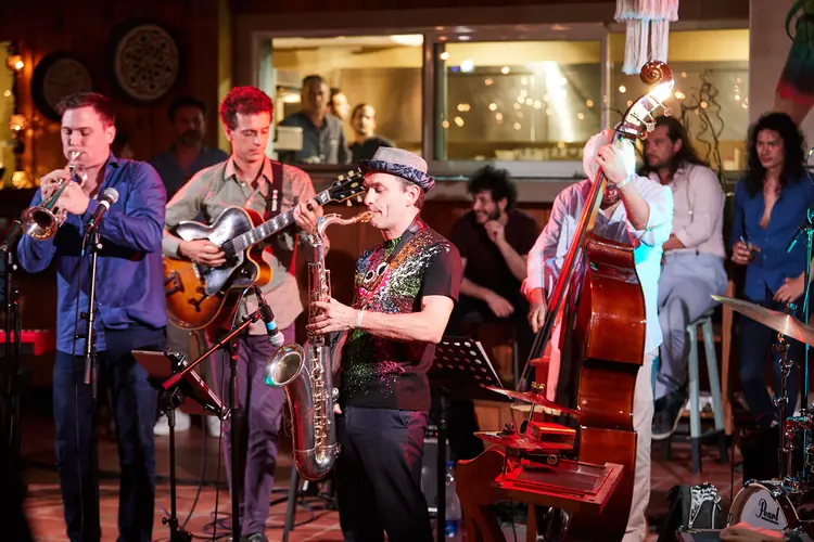 Jazz ensemble with trumpet, guitar, saxophone and double bass under warm stage lights — Jazz photography by Michaël Gramm