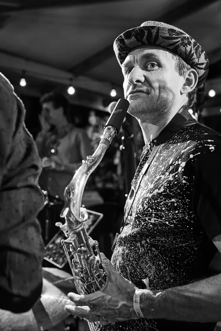 Saxophonist in a patterned cap holding his instrument, photographed in black and white — Jazz photography by Michaël Gramm